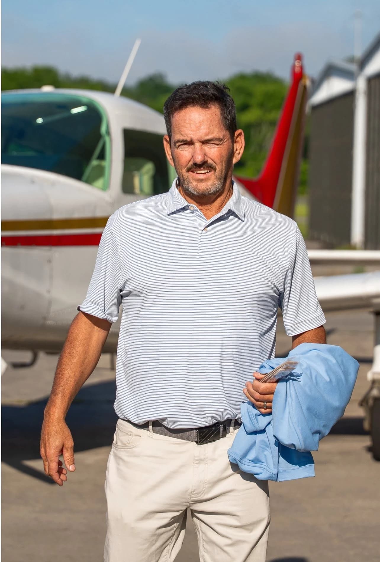 Standing beside a small airplane at an airfield