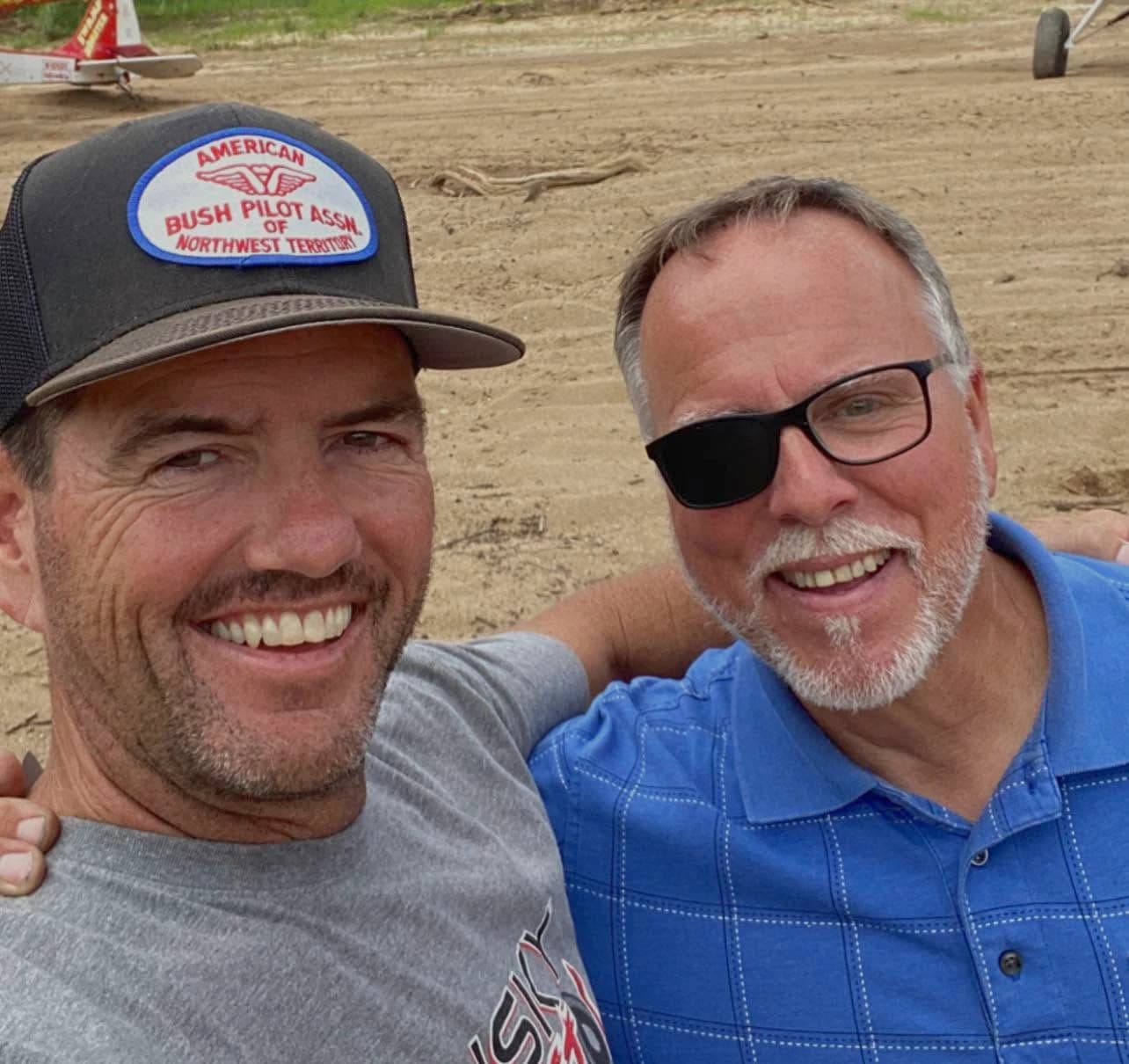 Two friends smiling for a selfie at an airfield