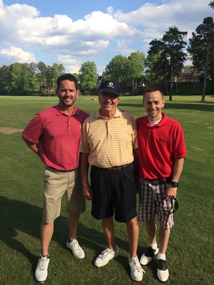 Three men in golf shirts on a golf course
