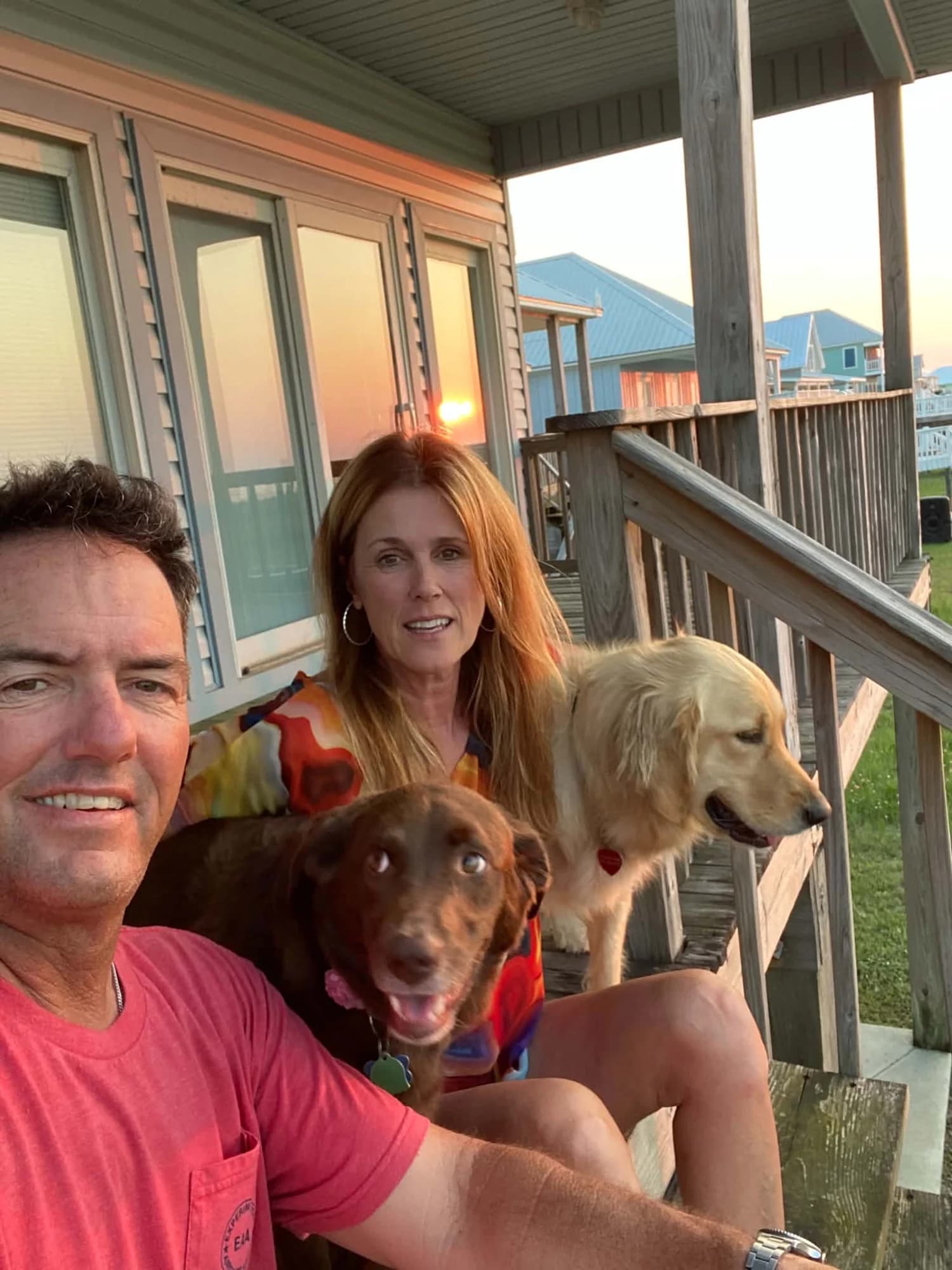 Frank on a porch at sunset with family and two dogs