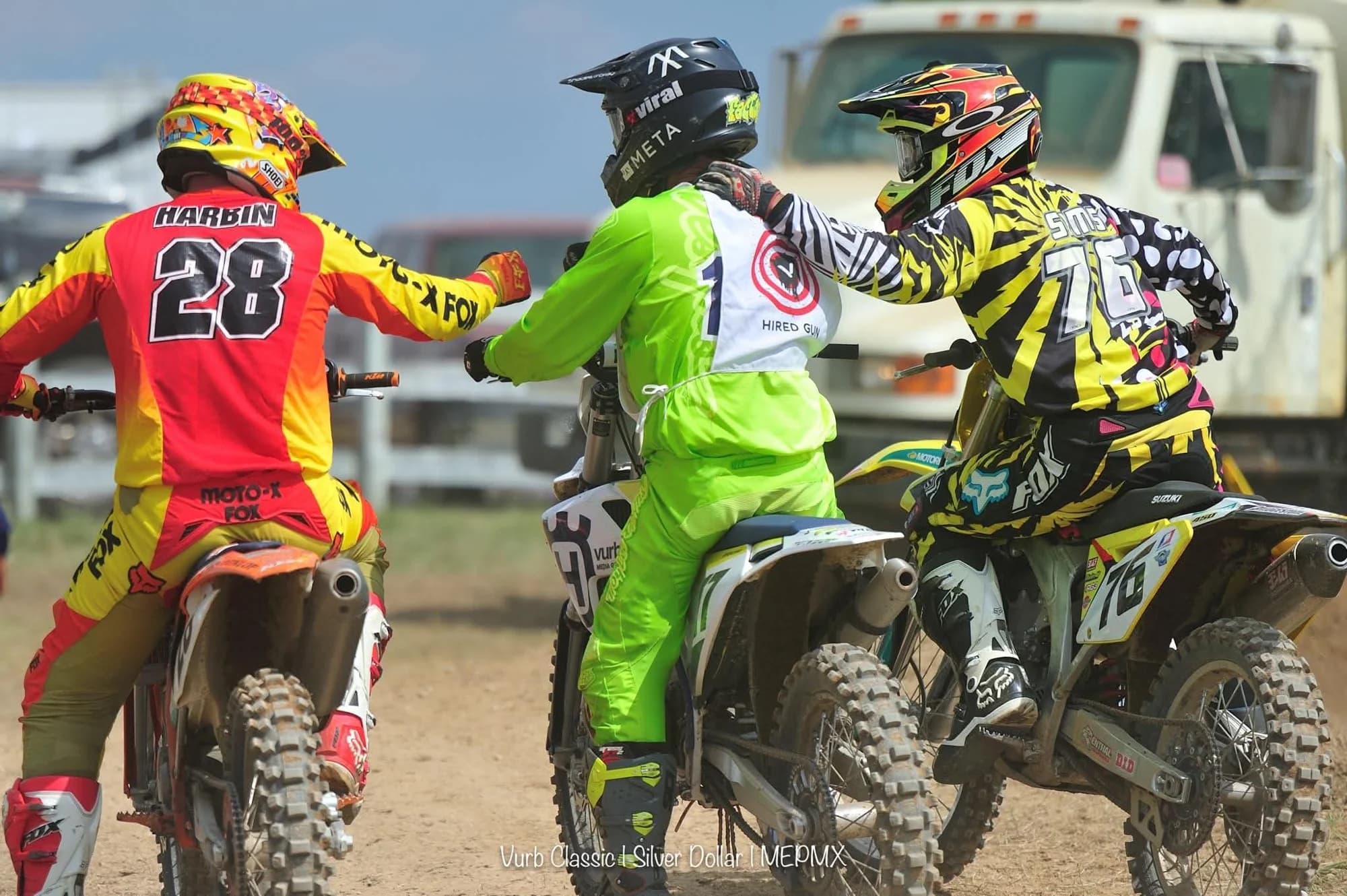 Three riders bumping fists at the start of a race