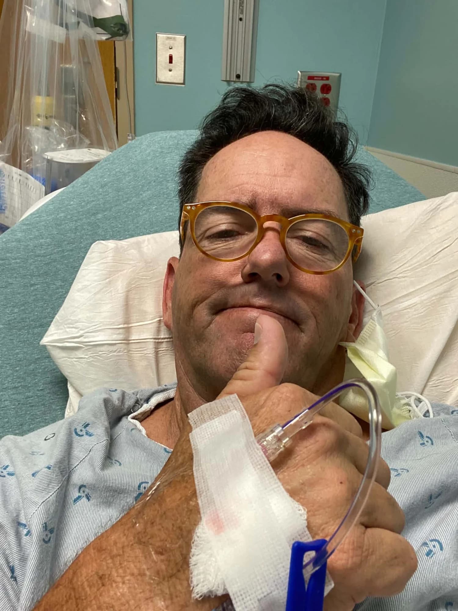 Frank giving a thumbs up from a hospital bed